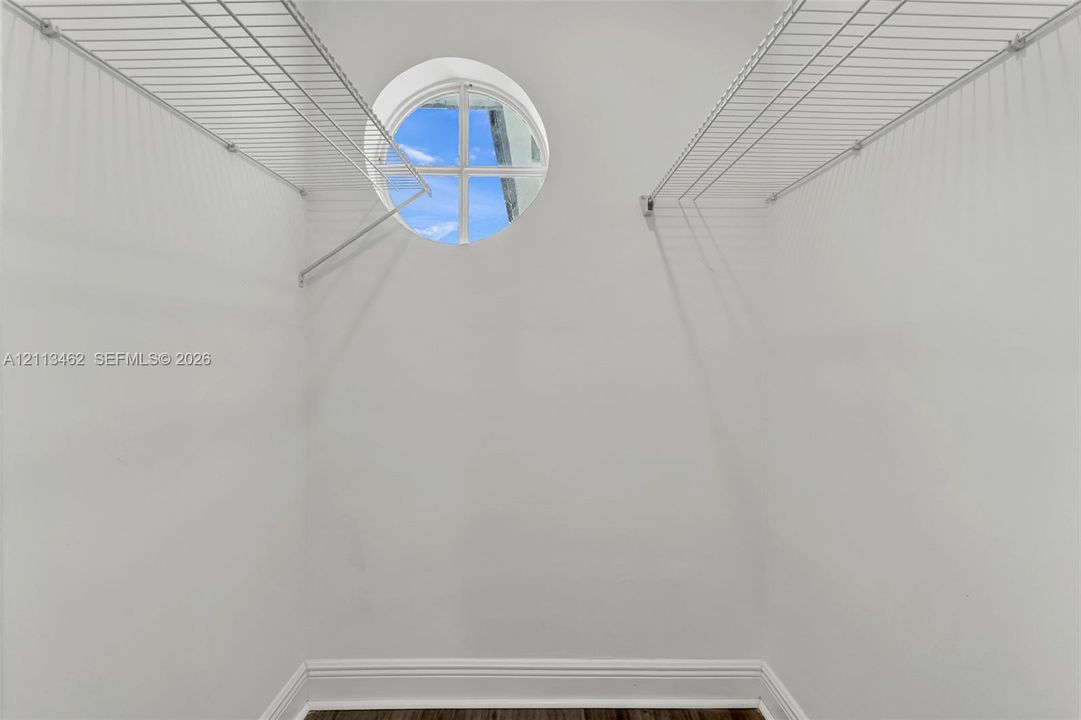 Storage space featuring white wire shelving and a circular window with divided light detail
