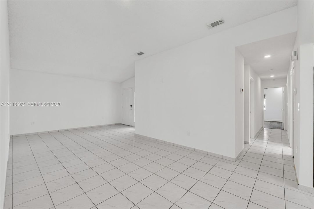 Open interior area featuring vaulted ceilings, neutral wall finishes, and light-toned tile flooring throughout