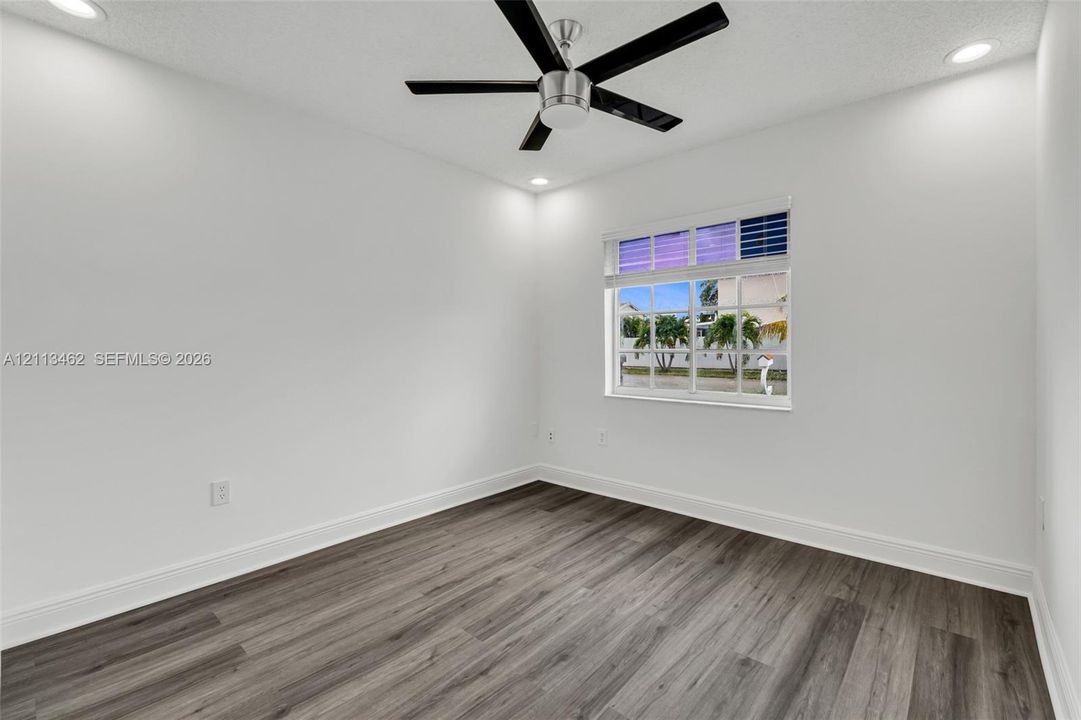 Room featuring wood-finish flooring, recessed lighting, and a multi-blade ceiling fan with integrated lighting