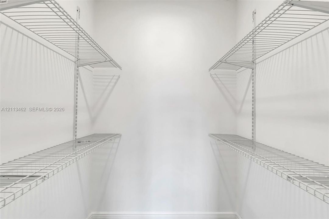 Storage space featuring dual-level white wire shelving units mounted on vertical wall tracks