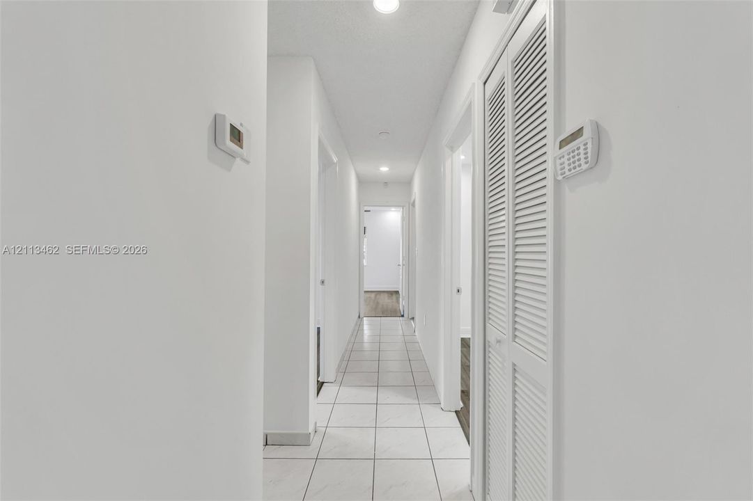 Hallway featuring white ceramic tile flooring, recessed lighting, and louvered bi-fold closet doors