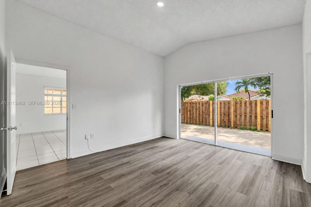 Vaulted ceilings, wood-finish flooring, recessed lighting, and sliding glass doors with access to an exterior patio