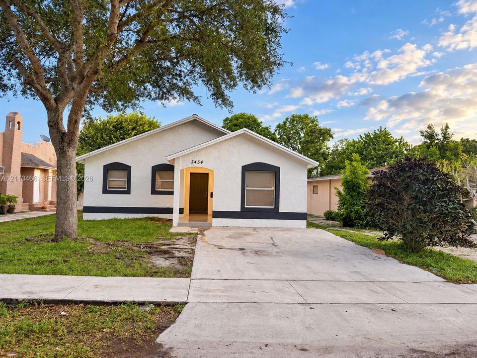 Stucco exterior featuring contrasting window trim, a concrete driveway, and a covered entryway