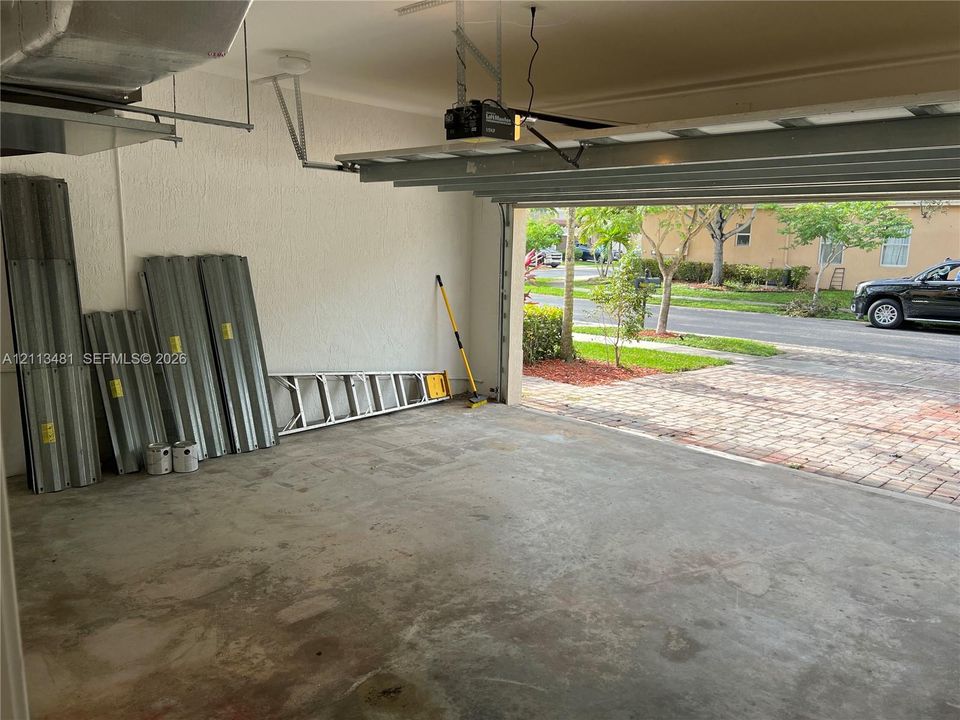 Attached two-car garage featuring concrete flooring, textured walls, and a ceiling-mounted automatic door opener
