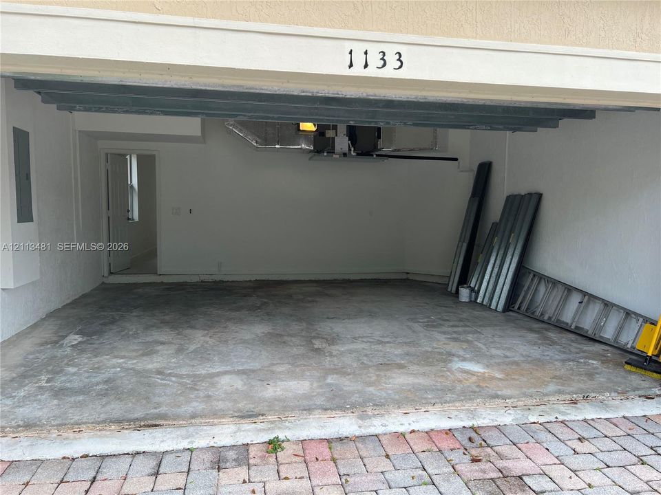 Attached two-car garage featuring a concrete floor, painted masonry walls, and a dedicated entry door