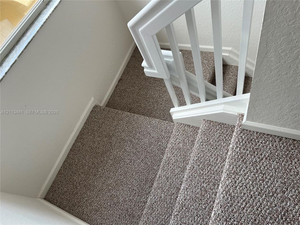 Staircase featuring wall-to-wall carpeting, white wooden balusters, and a matching handrail