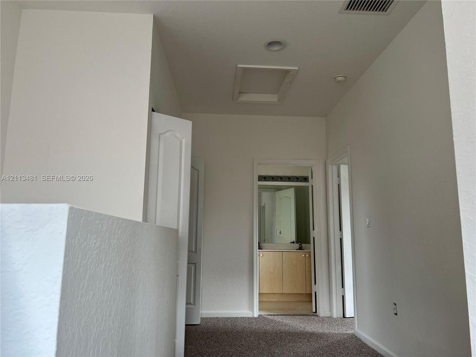 Hallway featuring neutral-toned carpeting, recessed ceiling lighting, and six-panel interior doors