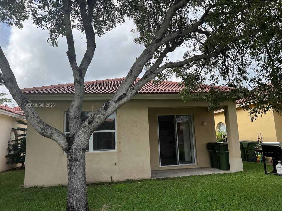 Stucco exterior featuring a tiled roof, covered patio, and glass sliding door