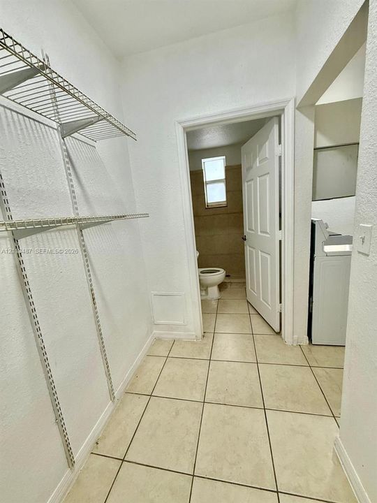 Utility space featuring metal wire shelving, neutral ceramic tile flooring, and a six-panel door