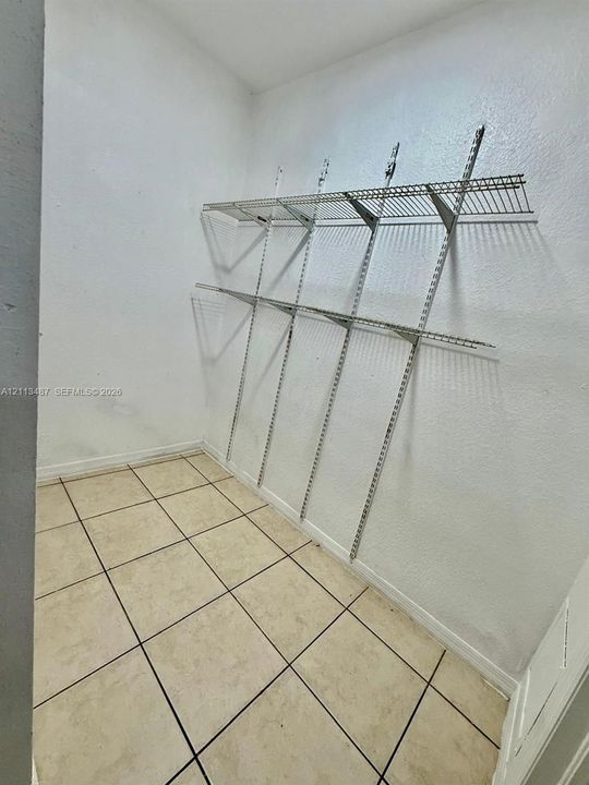 Storage space featuring ceramic tile flooring and white walls equipped with integrated wire shelving systems