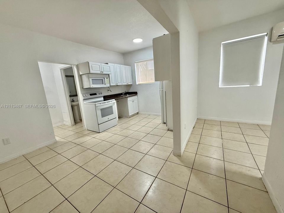Kitchen featuring white cabinetry, dark countertops, built-in microwave, white freestanding range, and tile flooring throughout