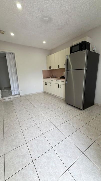 Kitchen featuring cream cabinetry, stainless steel refrigerator, built-in microwave, tile flooring, and recessed lighting
