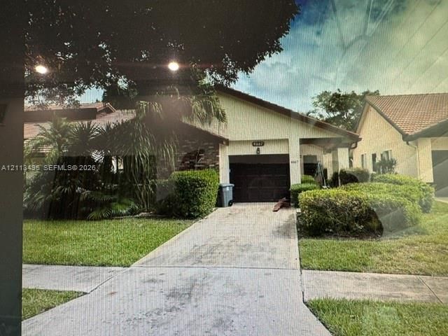 Single-story exterior featuring a gabled roofline, stucco facade, single-car garage, concrete driveway, and mature landscaping