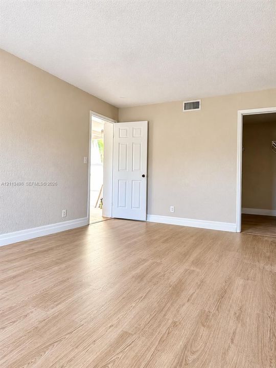 Neutral-toned interior featuring wood-finish flooring, textured walls, and a six-panel interior door
