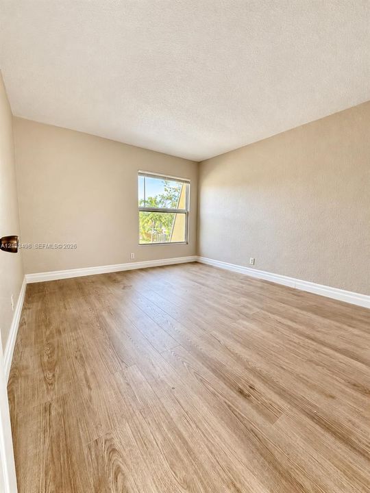 Neutral-toned interior space featuring light wood-finish flooring, a single-hung window with a exterior outlook, and smooth textured walls