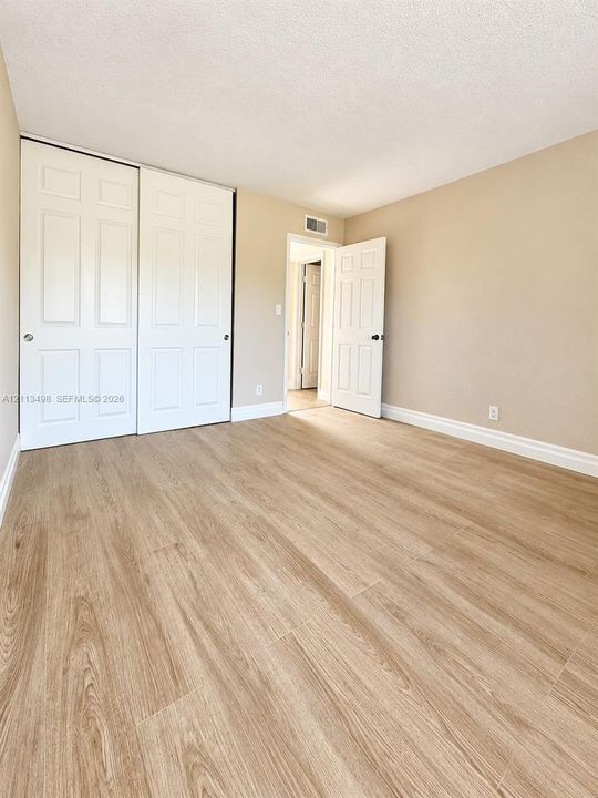 Neutral-toned interior featuring wood-finish flooring, white panel interior doors, and a double-door closet