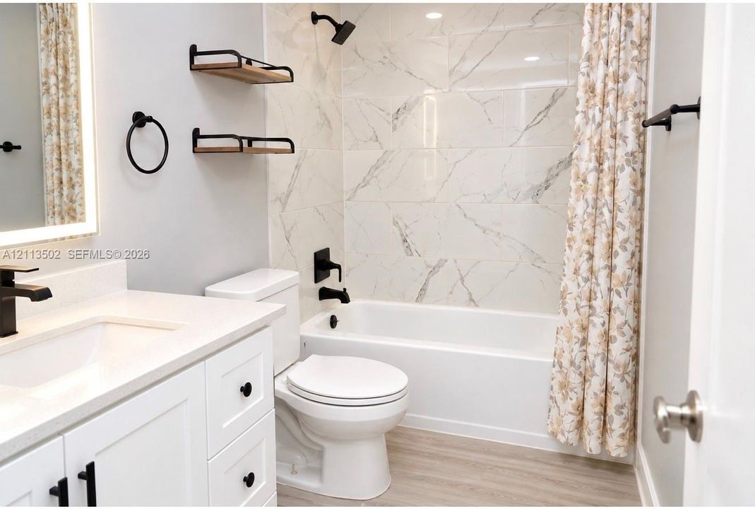 White vanity with stone-composite countertop, matte black fixtures, built-in floating wall shelves, and floor-to-ceiling tile shower surround