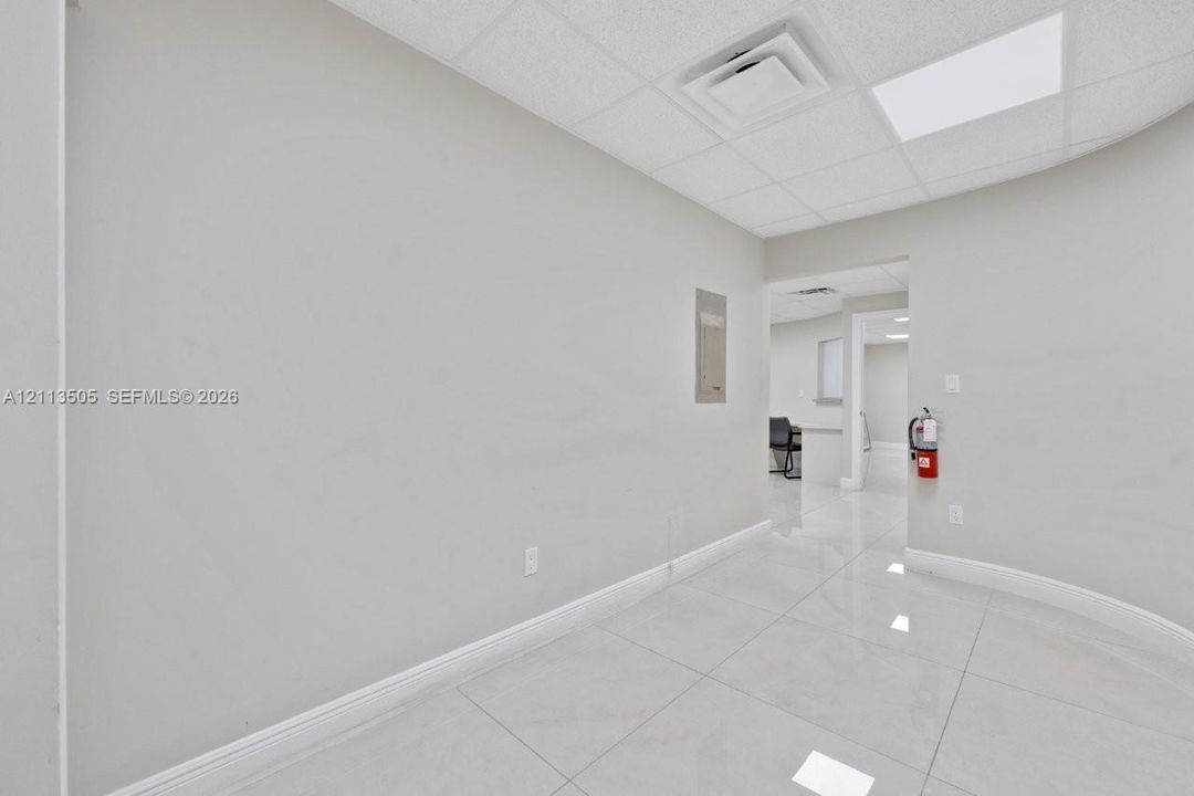 Neutral interior space featuring polished tile flooring, a drop ceiling with recessed lighting, and smooth-finish walls