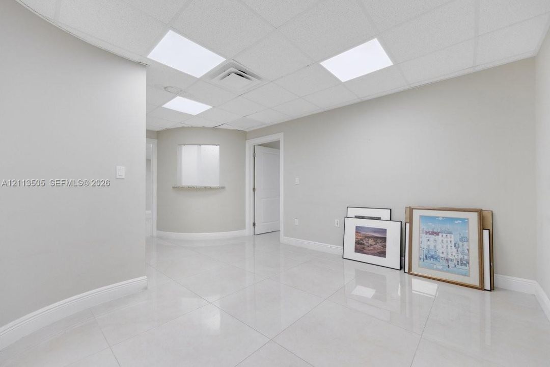 Interior space featuring light-toned tile flooring, recessed panel ceiling, and a curved alcove with a built-in pass-through window