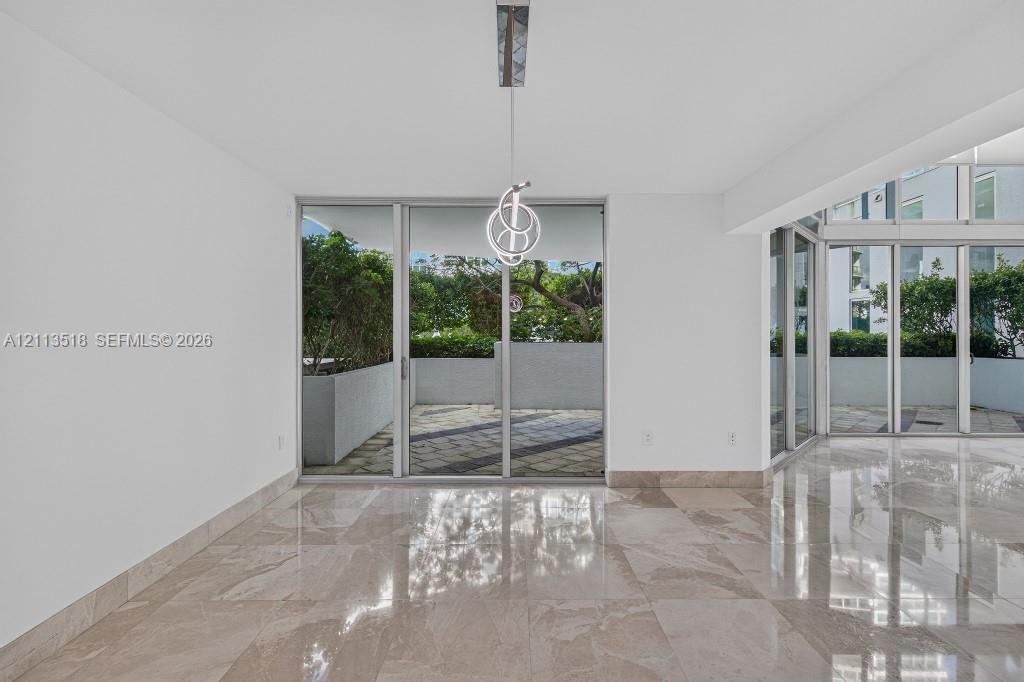 Polished stone flooring, floor-to-ceiling glass sliding doors, built-in contemporary pendant lighting, and an expansive exterior terrace with masonry planters