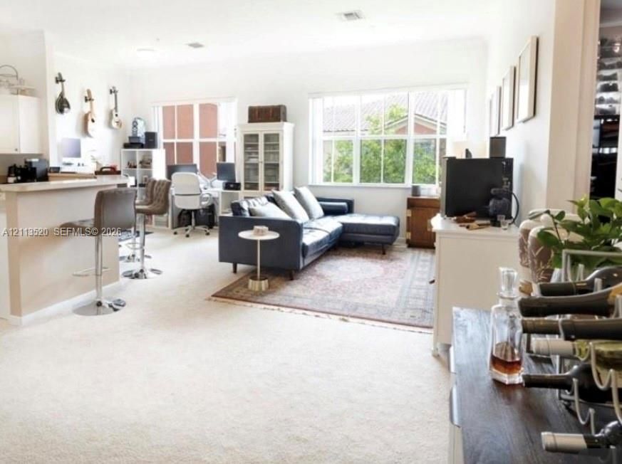 Open-concept interior featuring wall-to-wall carpeting, multi-pane windows, and a built-in kitchen peninsula with a flat surface counter