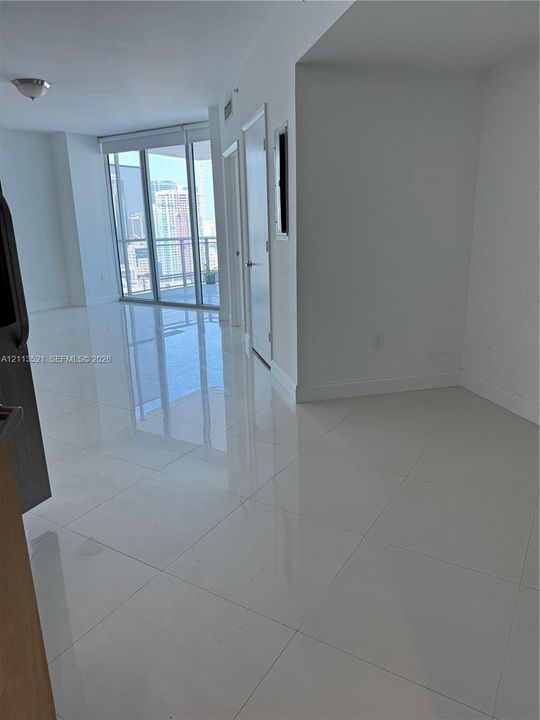 Polished large-format tile flooring, floor-to-ceiling glass sliding doors, and access to a private balcony