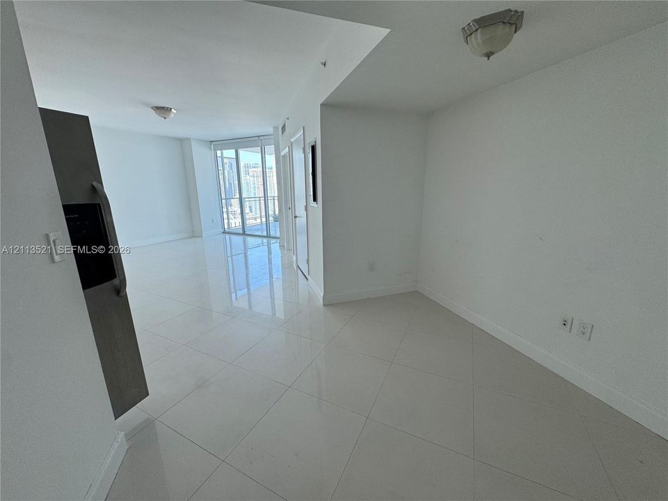 Interior space featuring high-gloss tile flooring, floor-to-ceiling glass sliding doors, a stainless steel refrigerator, and flush-mount ceiling lighting