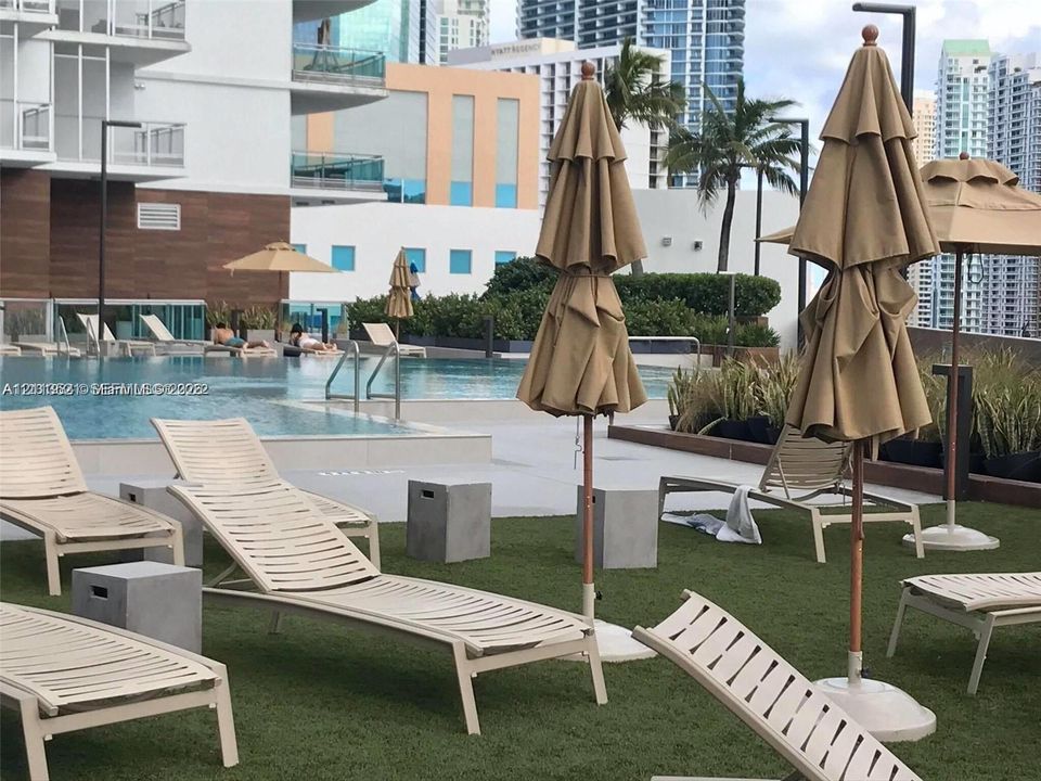 Outdoor pool featuring tile surround, synthetic turf deck, and perimeter landscaping