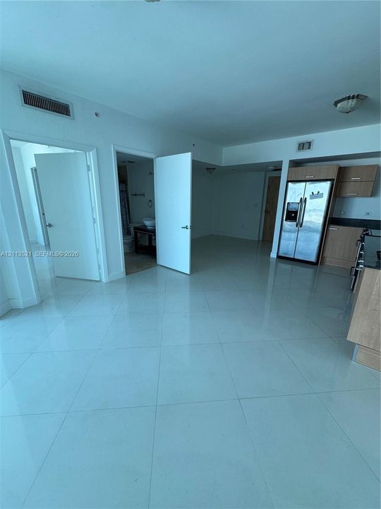 Open-concept interior featuring large-format tile flooring, flat-panel wood-finish cabinetry, stainless steel refrigerator, and flush-mount ceiling lighting