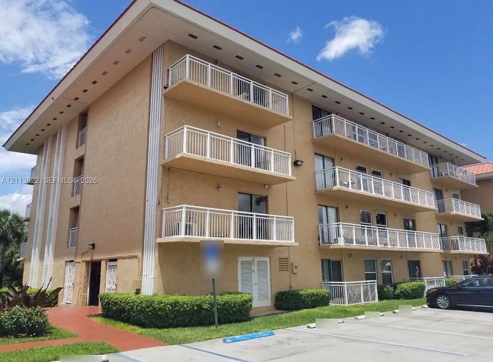 Multi-story exterior featuring a textured facade, stacked balconies with white railings, and a wide roof overhang
