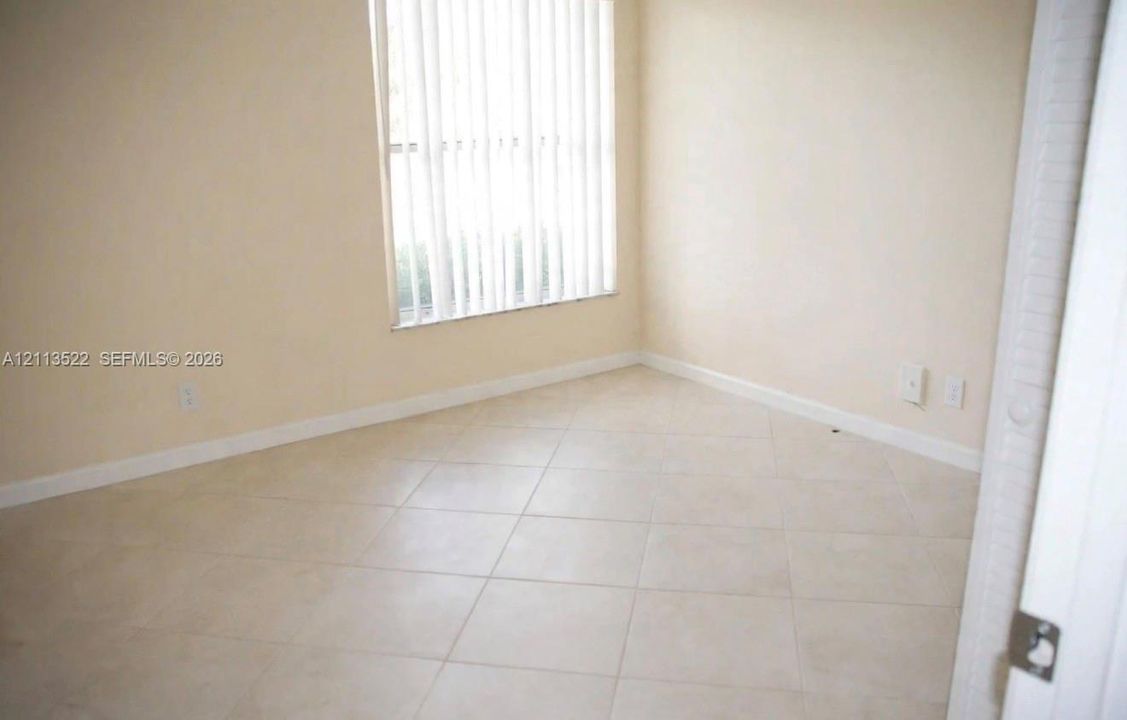 Neutral-toned ceramic tile flooring, vertical window blinds, and crisp off-white wall finishes