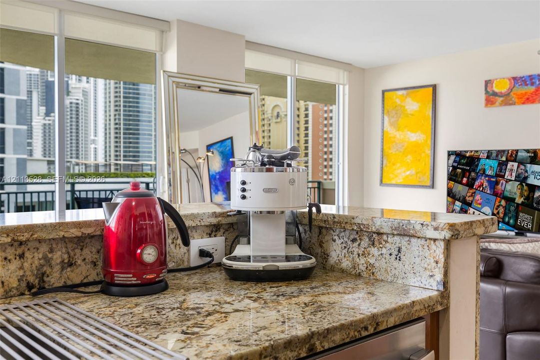 Kitchen featuring stone countertops with a breakfast bar, stainless steel appliance, and floor-to-ceiling windows