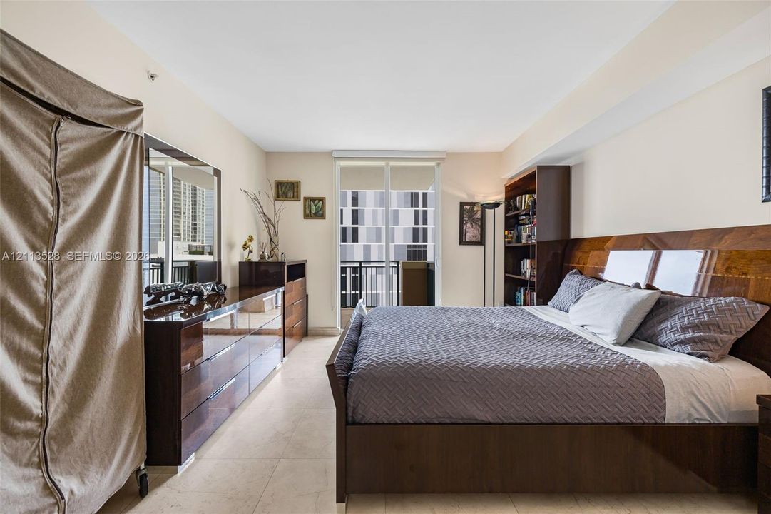 Sliding glass door opening to a balcony, stone-finish flooring, and high ceilings