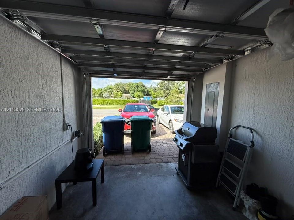Garage interior featuring a concrete floor, textured wall finish, and an electrical breaker panel