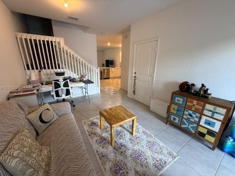 Ceramic tile flooring throughout with a white wooden staircase railing and a panel-style interior door