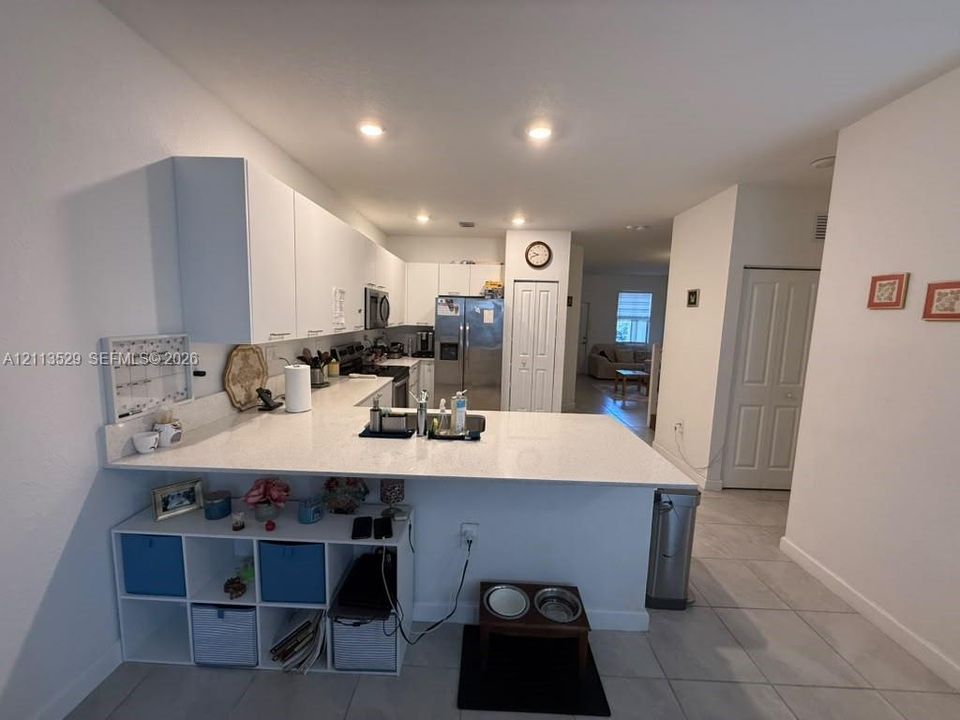 Kitchen featuring a peninsula with a stone-finish countertop, white cabinetry, stainless steel appliances, recessed lighting, and tile flooring