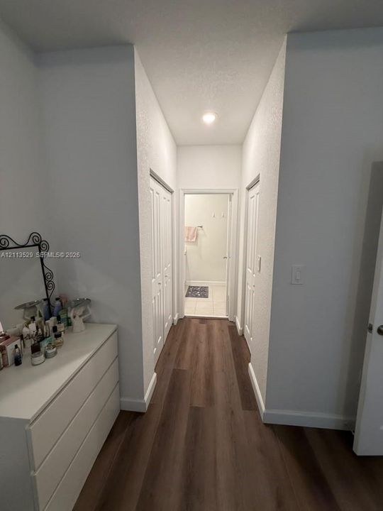 Hallway featuring wood-finish flooring, two sets of white bi-fold closet doors, and recessed lighting