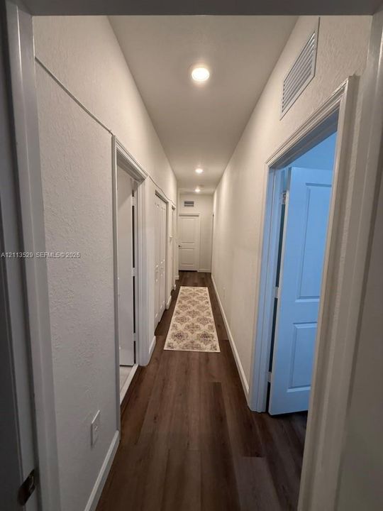 Hallway featuring wood-finish flooring, recessed lighting, and white multi-panel interior doors