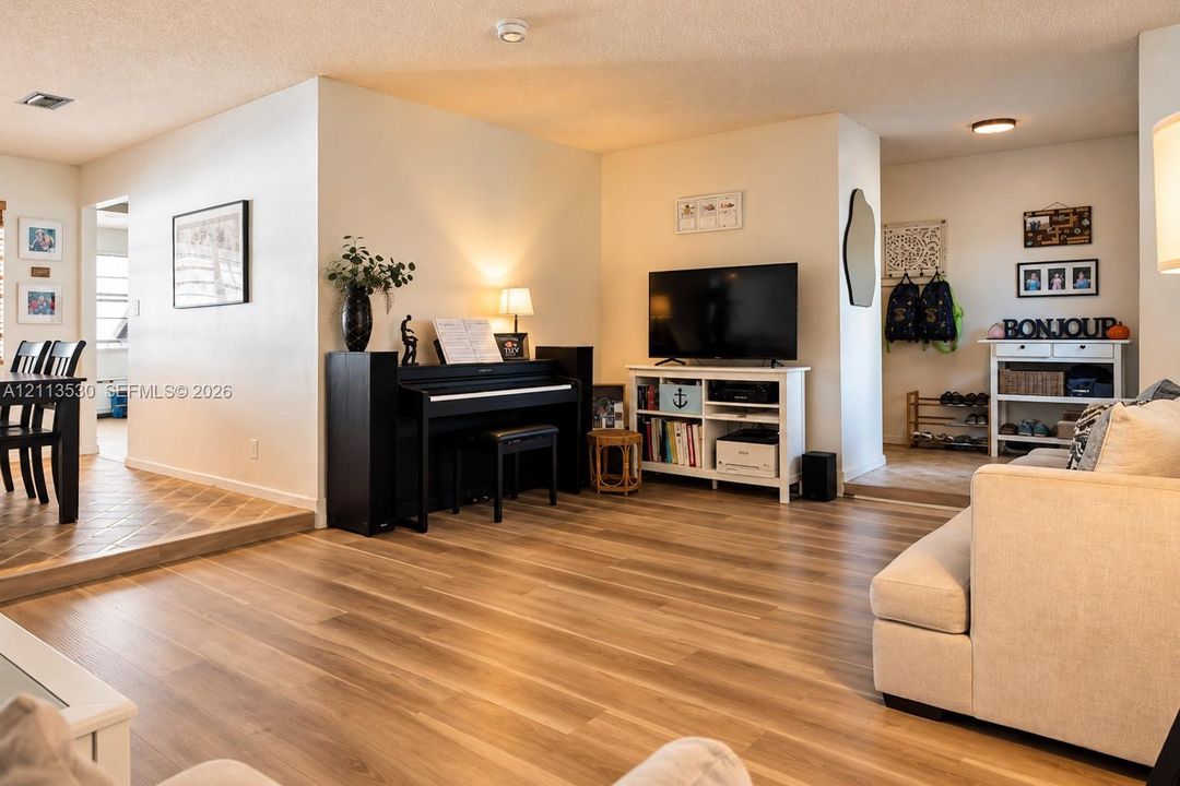 Open-concept interior featuring wood-finish flooring, a step-down dining area with tiled flooring, and recessed ceiling lighting
