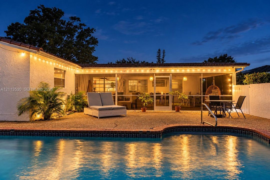 Exterior swimming pool with brick coping, screened-in patio, and aggregate stone hardscaping
