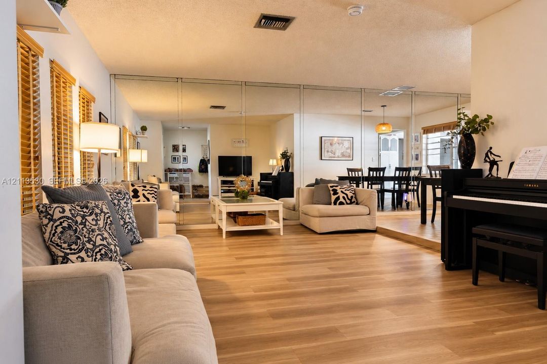 Wood-finish flooring, full-wall mirrored paneling, and elevated platform area