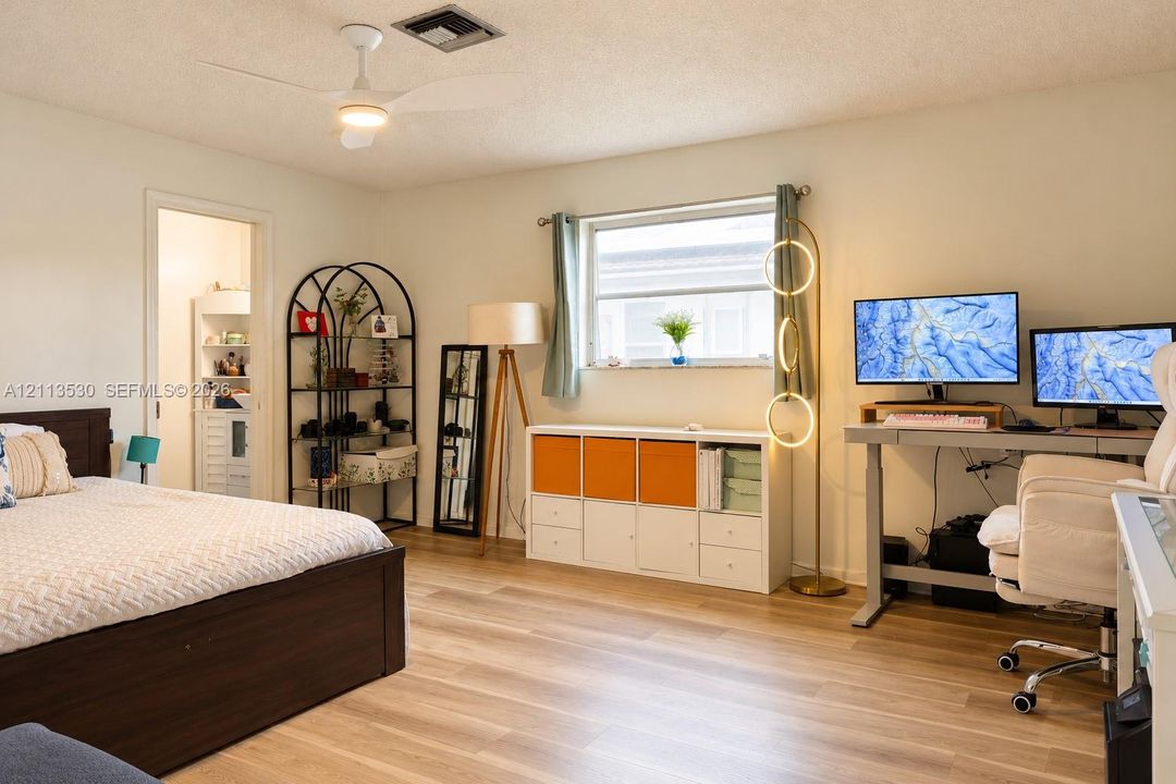 Room featuring wood-finish flooring, a neutral color palette, a ceiling fan with integrated lighting, and a single-pane window