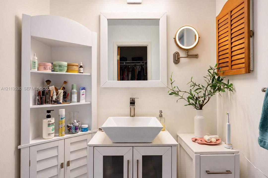 Vanity featuring a white square vessel sink, polished faucet, integrated built-in corner shelving, and a framed mirror