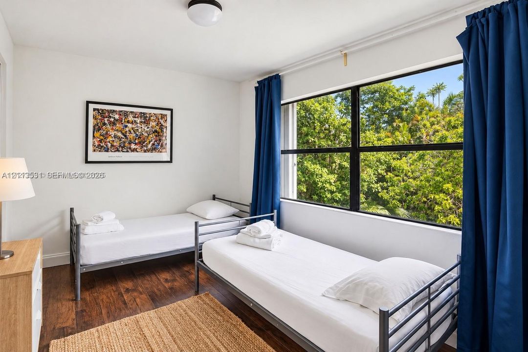 Room featuring wood-finish flooring, a large window with black framing, and a flush-mount ceiling light fixture