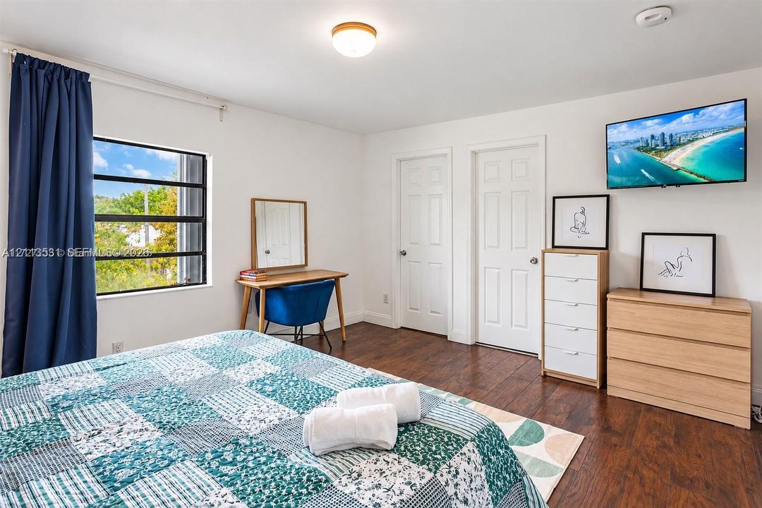 Wood-finish flooring, multi-pane window with dark framing, flush-mount ceiling lighting, and two interior doors with panel detailing