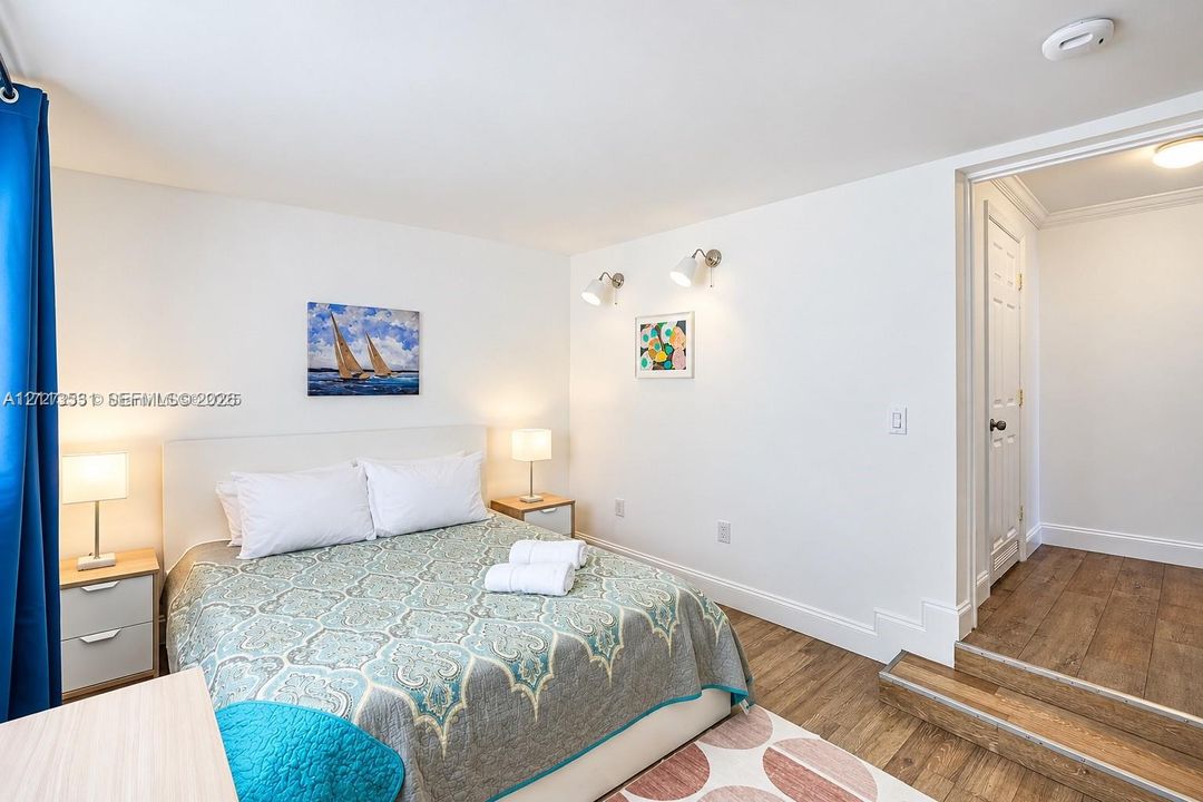 Wood-finish flooring, white walls, dual wall-mounted adjustable light fixtures, and a six-panel interior door
