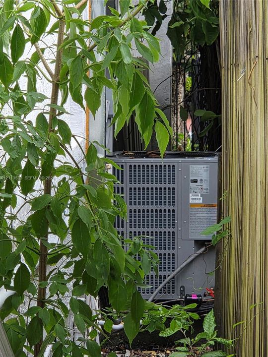 Exterior air conditioning unit featuring a gray metal housing and wire mesh protective grille