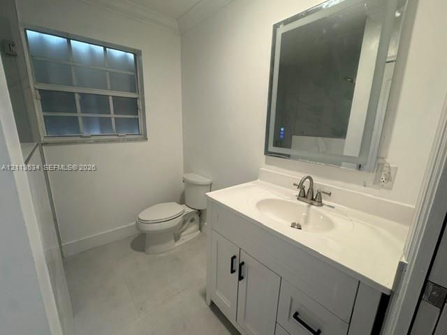 White vanity featuring a solid-surface countertop with an integrated basin, contemporary cabinetry with matte black hardware, and an LED-lit mirror