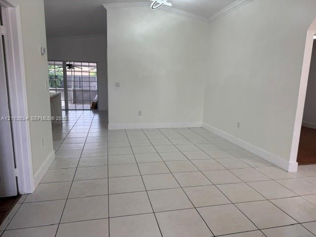 Neutral-toned ceramic tile flooring, vaulted ceilings with crown molding, and an arched entryway