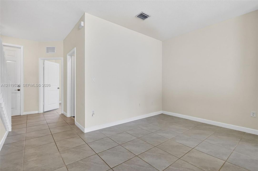 Neutral-toned interior space featuring large-format ceramic tile flooring, solid-core interior doors, and smooth-finish walls